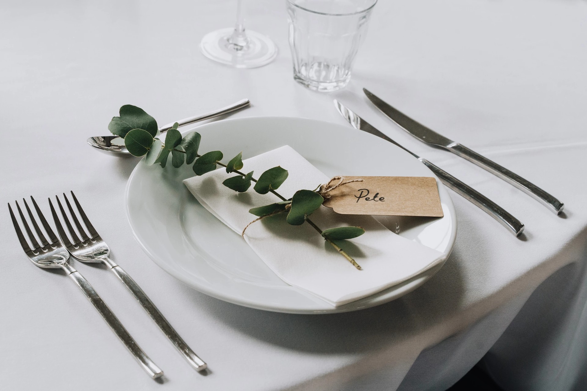 Elegantly arranged wedding reception table at Clarence Hall, with a white tablecloth, exquisite silverware, and a green leaf decoration, exuding sophistication and anticipation.