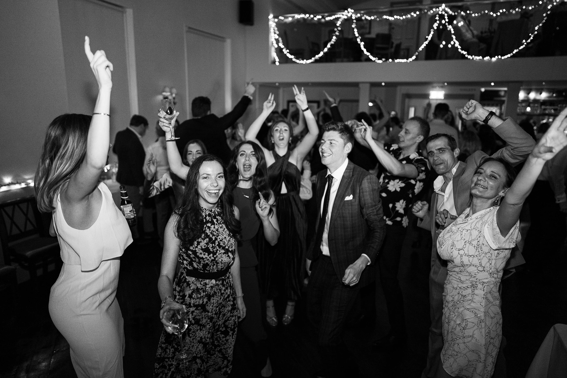 Wedding reception with dancing guests under string lights, capturing a festive atmosphere ideal for celebrations at The Admiral Hardy.