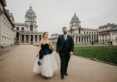 A couple in formal attire walking hand in hand in front of a grand building, capturing a moment of joy and celebration at Clarence Hall.
