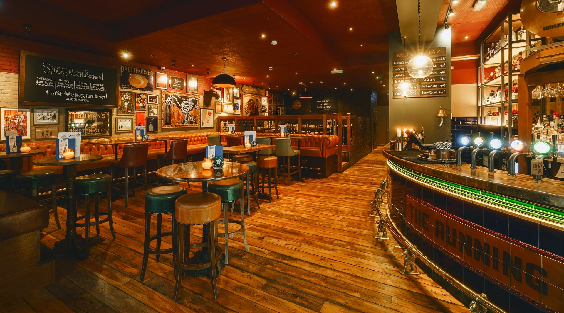 The image shows a cozy, well-lit bar with a curved wooden counter, bar stools, and a large mirror. The bar is filled with various drinks and has a menu board with German and English text. The wooden floor and ceiling create a warm and inviting atmosphere, while the black and white color scheme adds sophistication. The bar is a hub of activity, with patrons enjoying their drinks and conversation.