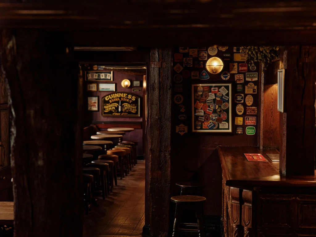 A gold trophy and a white and blue soccer ball are on a vibrant green field, with the trophy slightly to the left and the ball to the right. The background features a blurred stadium with red and blue seats, suggesting a soccer match. The image captures a moment of triumph and celebration.